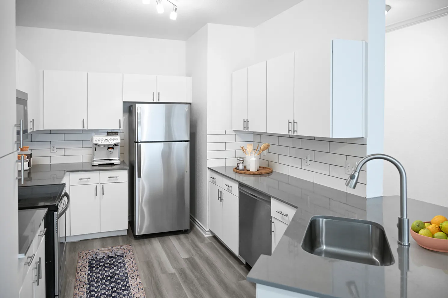 Sleek, modern kitchen with stainless steel appliances, white cabinetry, and elegant gray countertops.