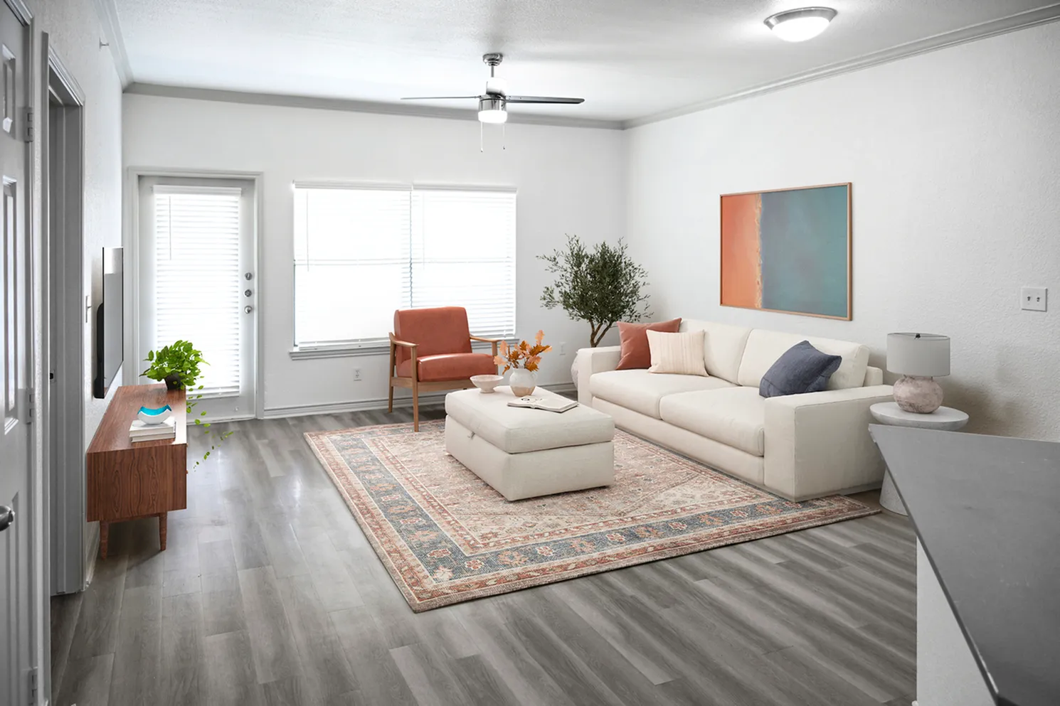 Bright and inviting living room with modern furniture, a plush area rug, and stylish artwork, featuring large windows for natural light.