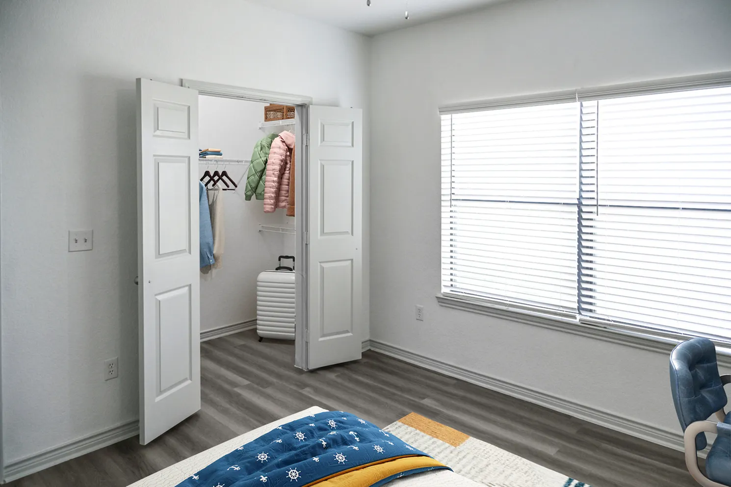 Bright bedroom with sleek flooring and a spacious walk-in closet, enhancing modern living.