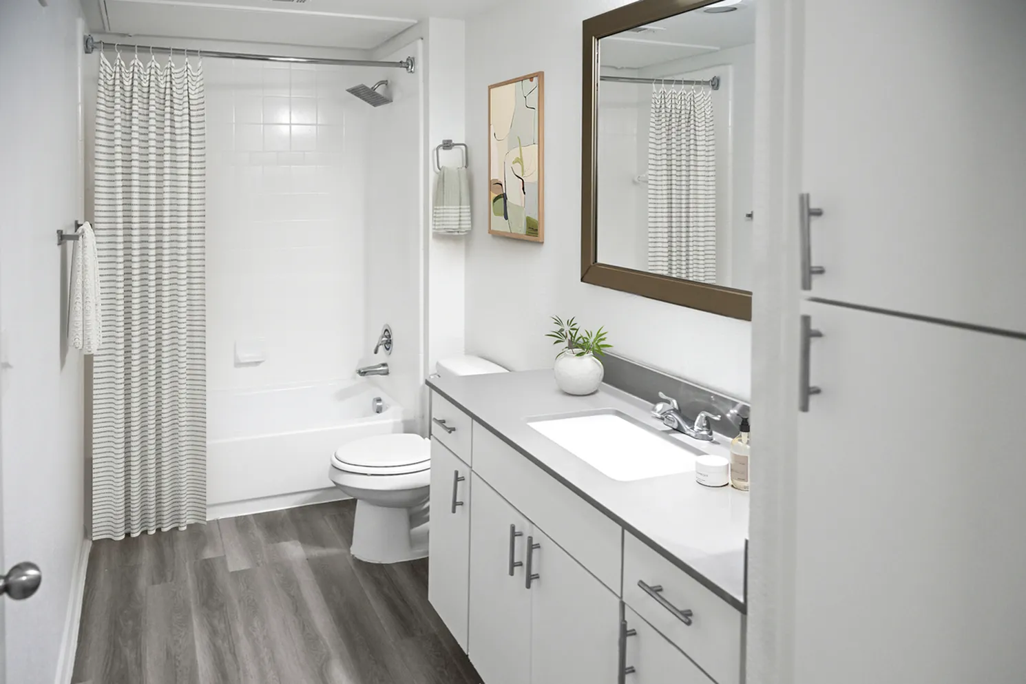 Modern bathroom featuring sleek white cabinetry, elegant fixtures, and stylish wood flooring, perfect for a serene retreat.