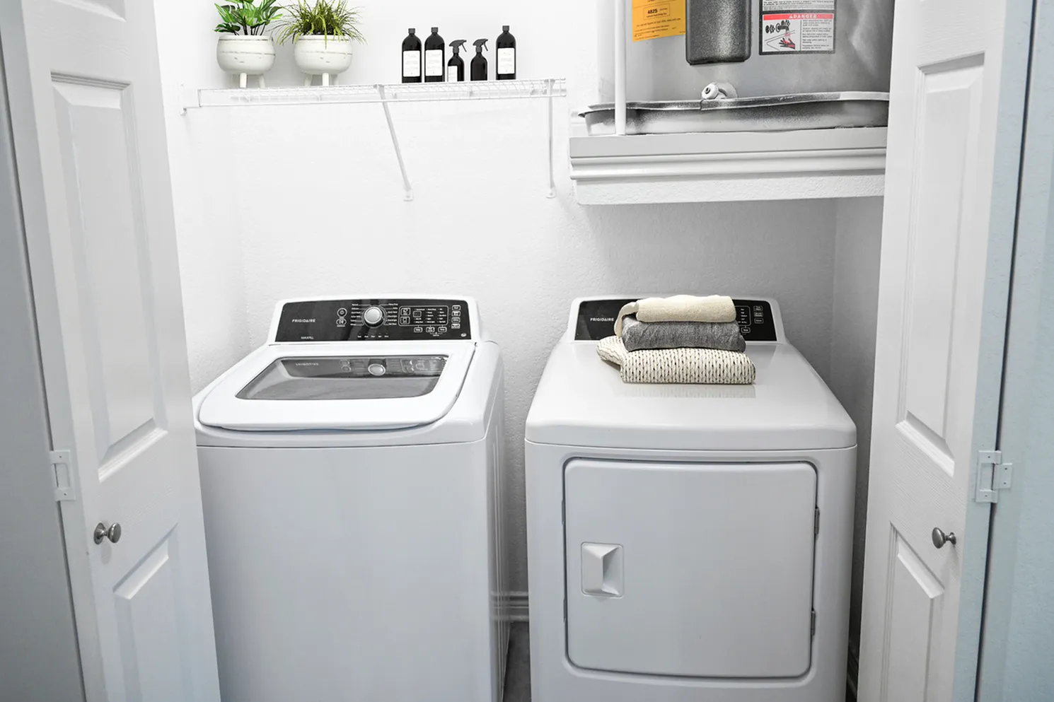 Modern laundry room with energy-efficient washer and dryer, featuring sleek design and organized storage shelf.