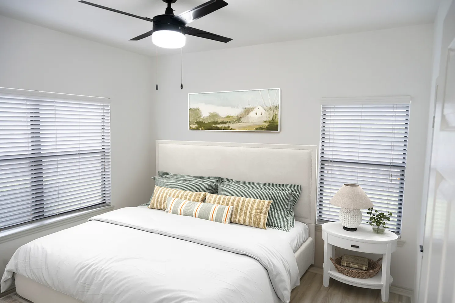 Bright and cozy bedroom with a modern ceiling fan, soft lighting, and nature-inspired decor.