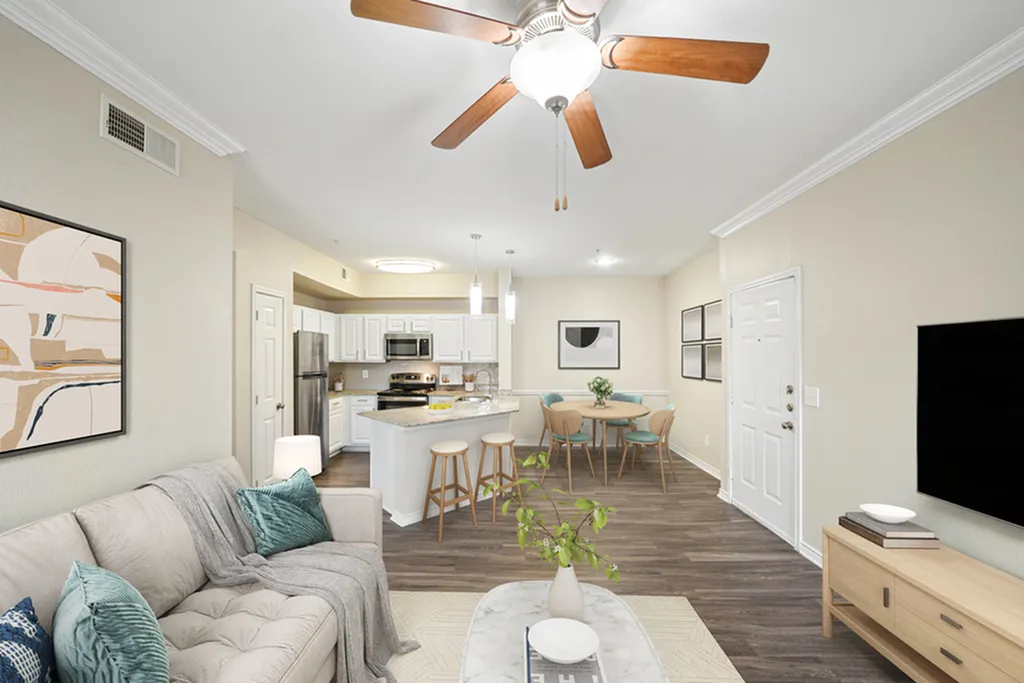 Modern open-concept living room with chic decor, featuring a bright kitchen with an island, cozy dining area, and elegant ceiling fan.