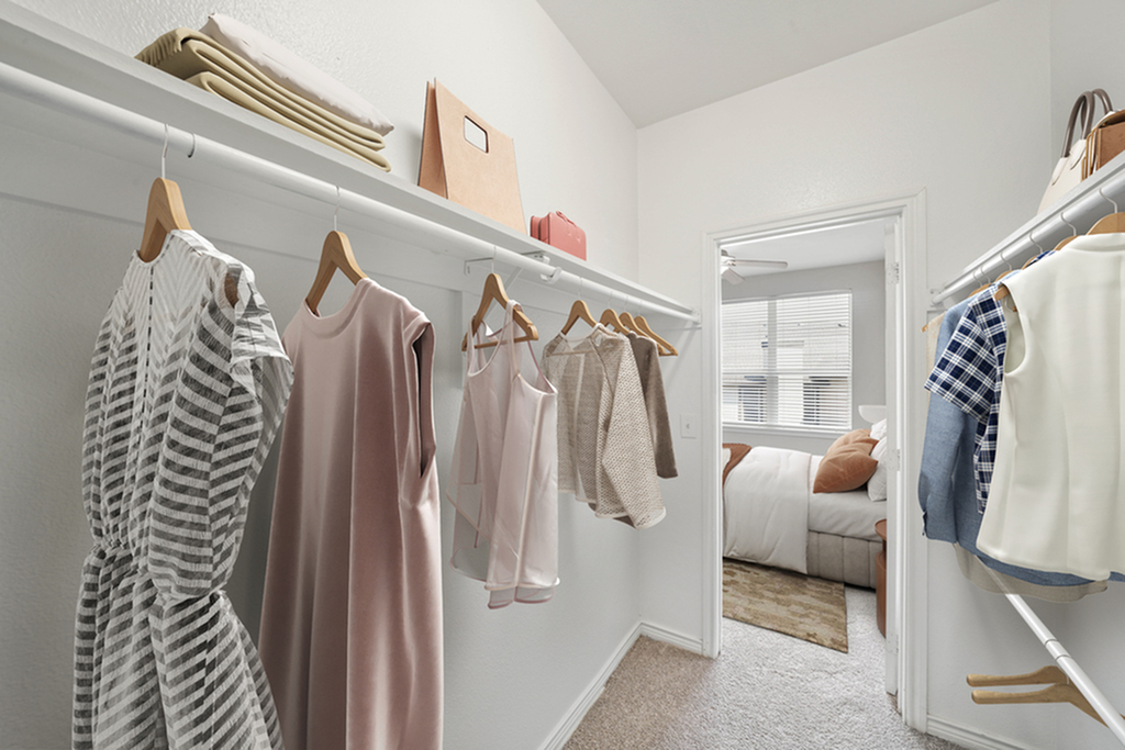 Spacious walk-in closet with stylish clothing, leading to a cozy bedroom with natural light.
