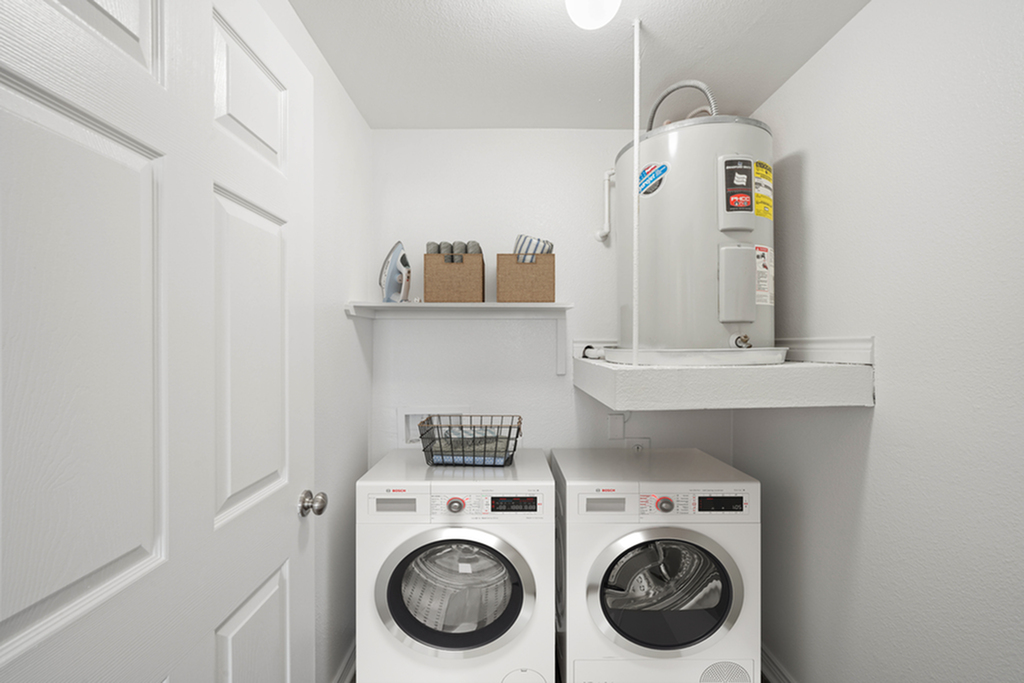 Modern laundry room featuring a washer and dryer with convenient shelving for storage, alongside a sleek water heater.