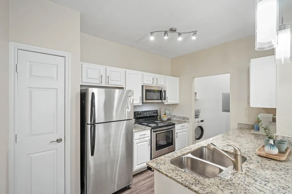 Open concept kitchen with granite counters, pendant lighting, wood floors, stainless appliances, white cabinets, and wooden floors