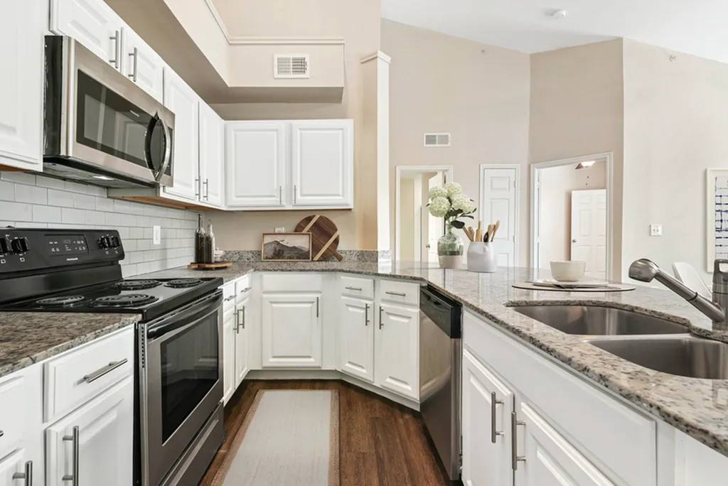 Modern kitchen with sleek granite countertops, stainless steel appliances, and elegant white cabinetry.