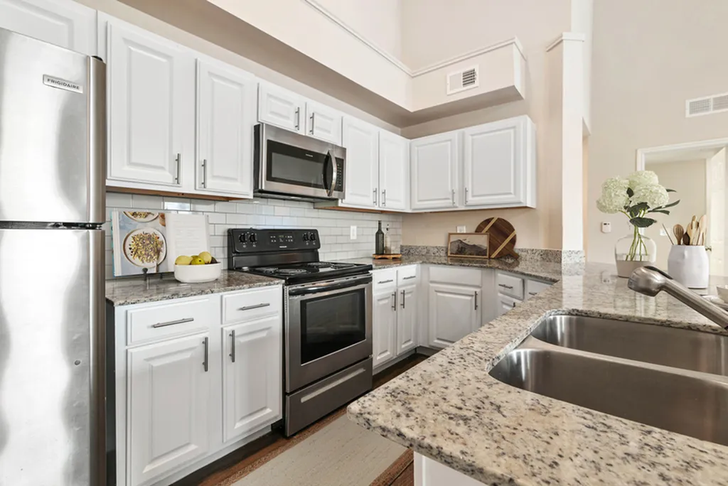 Kitchen with white cabinetry, granite counters, stainless steel appliances, undermount sink, and white tile backsplash,