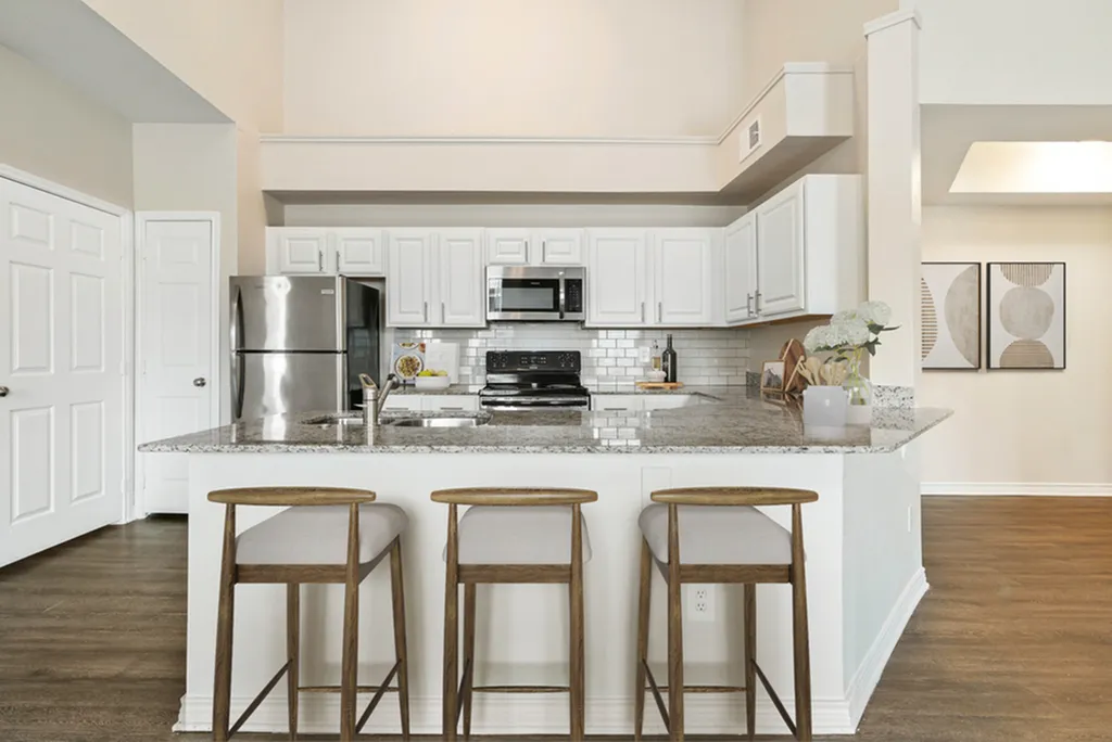 Modern kitchen with sleek granite countertops, stainless steel appliances, and stylish bar seating.