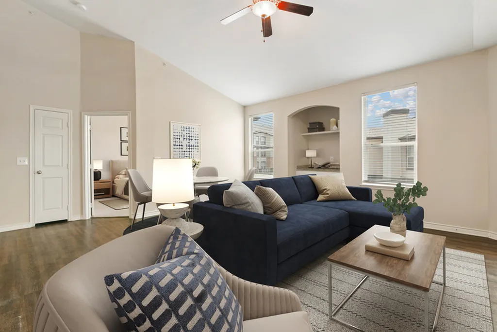 Bright and airy living room featuring a modern navy sofa, elegant decor, and large windows showcasing a scenic view.
