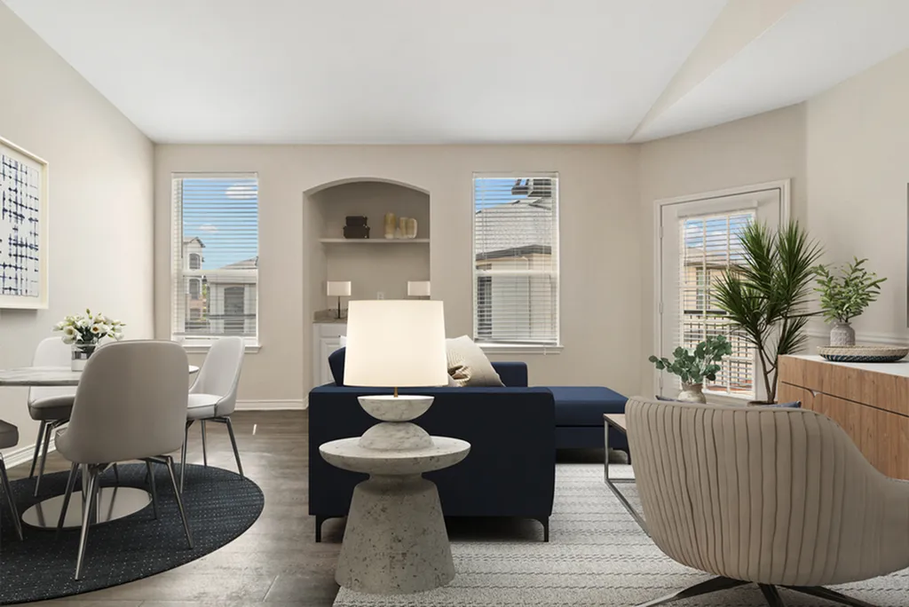 Bright and inviting living room with modern decor, featuring a comfortable navy sofa, elegant dining area, and large windows with abundant natural light.