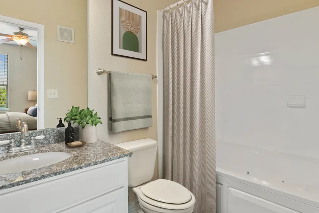 Bathroom with granite counter top, vanity lighting, toilet, bath tub