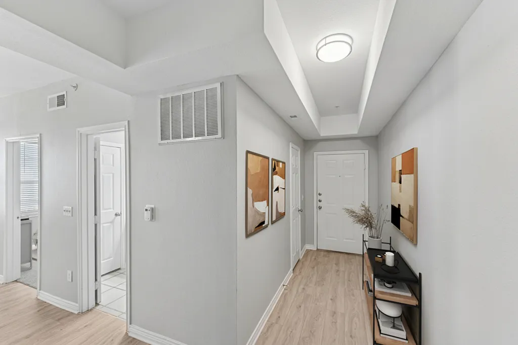 Entry way with door, hard wood flooring, entry table, potted plant and wall art