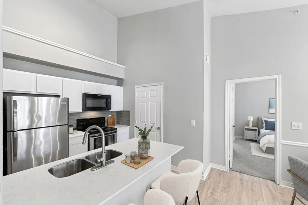 Kitchen with stainless steel appliance, white quartz counters, gooseneck faucet, creme chairs, and hardwood floors
