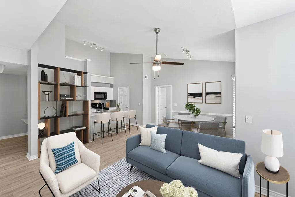 Open concept living room with ceinig fan, hard wood flooring, blue couch, round coffee table, dining area with table and chairs
