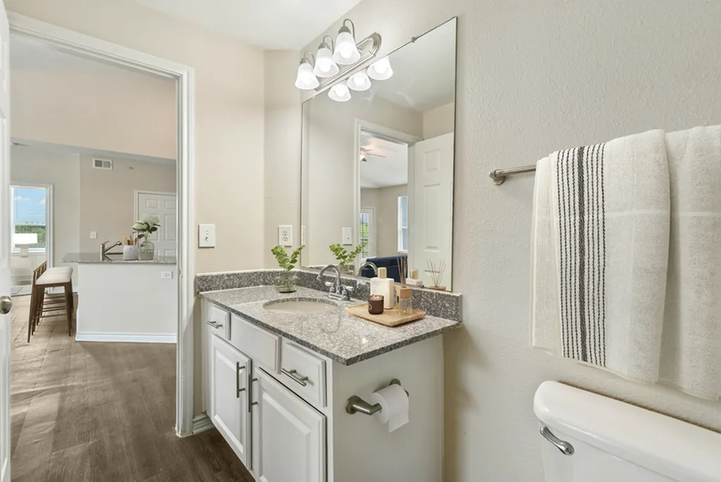 Secondary bathroom with granite counters and large vanity mirror with lighting