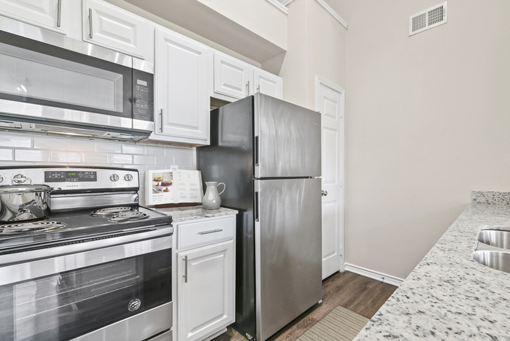 Modern kitchen featuring stainless steel appliances, granite countertops, and white shaker cabinetry.