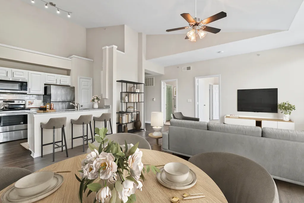 Contemporary open-concept living area with a modern kitchen, stylish decor, and natural light filtering through high ceilings.