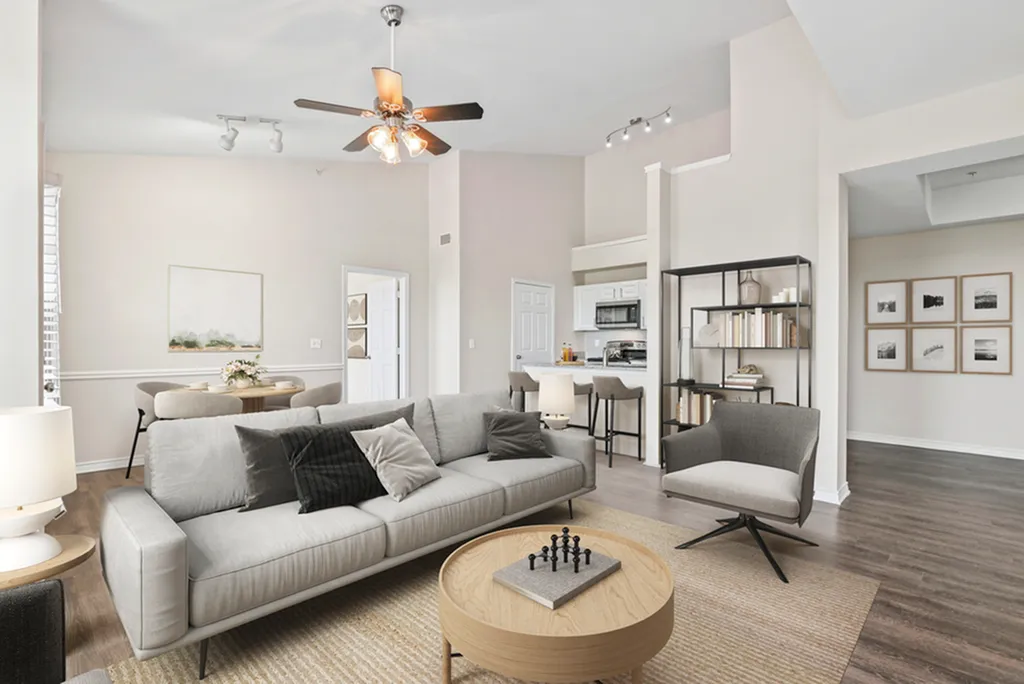 Modern open-concept living room featuring elegant neutral decor, cozy seating area, and sleek kitchen with a breakfast bar.