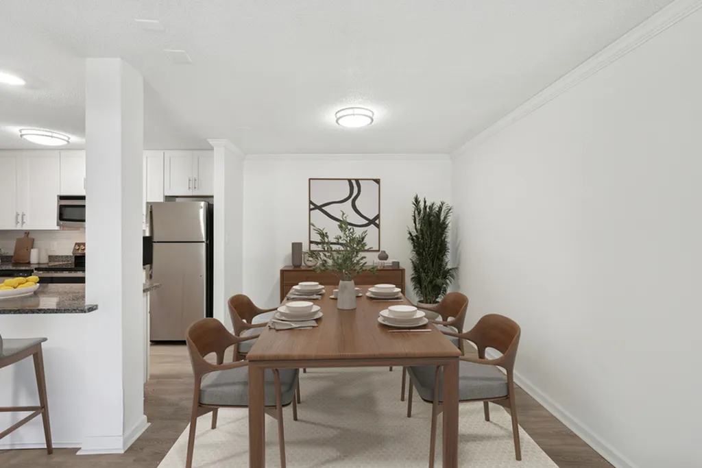 Elegant dining area with a modern wooden table set for six, adjacent to a sleek kitchen with stainless steel appliances and contemporary decor.