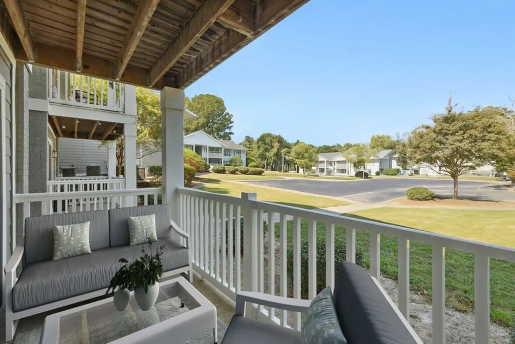 Charming balcony with cozy seating overlooking a peaceful, landscaped community.