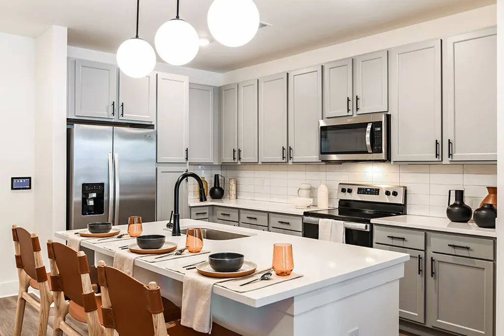Modern kitchen with sleek gray cabinets, stainless steel appliances, and a stylish island with seating for four.