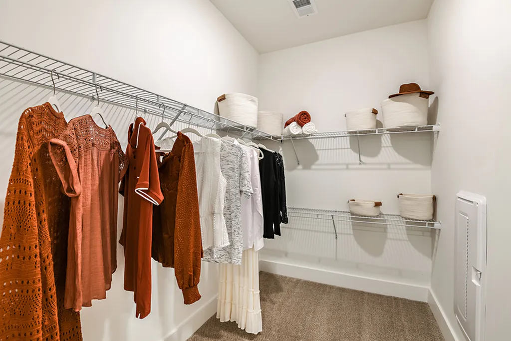 Spacious walk-in closet featuring organized shelving, modern storage baskets, and vibrant clothing for a stylish living space.