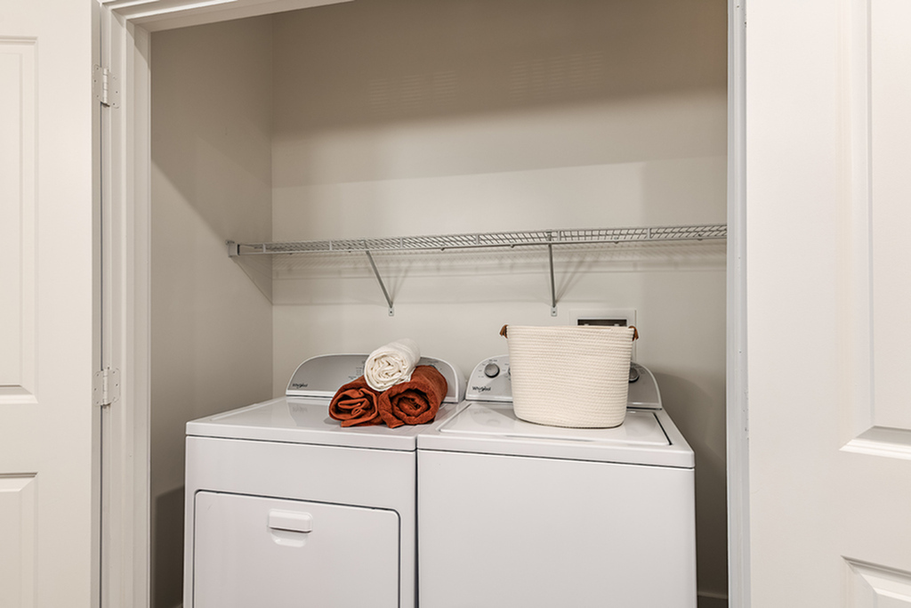 Modern laundry room with washer and dryer, neatly organized with towels and a storage basket.