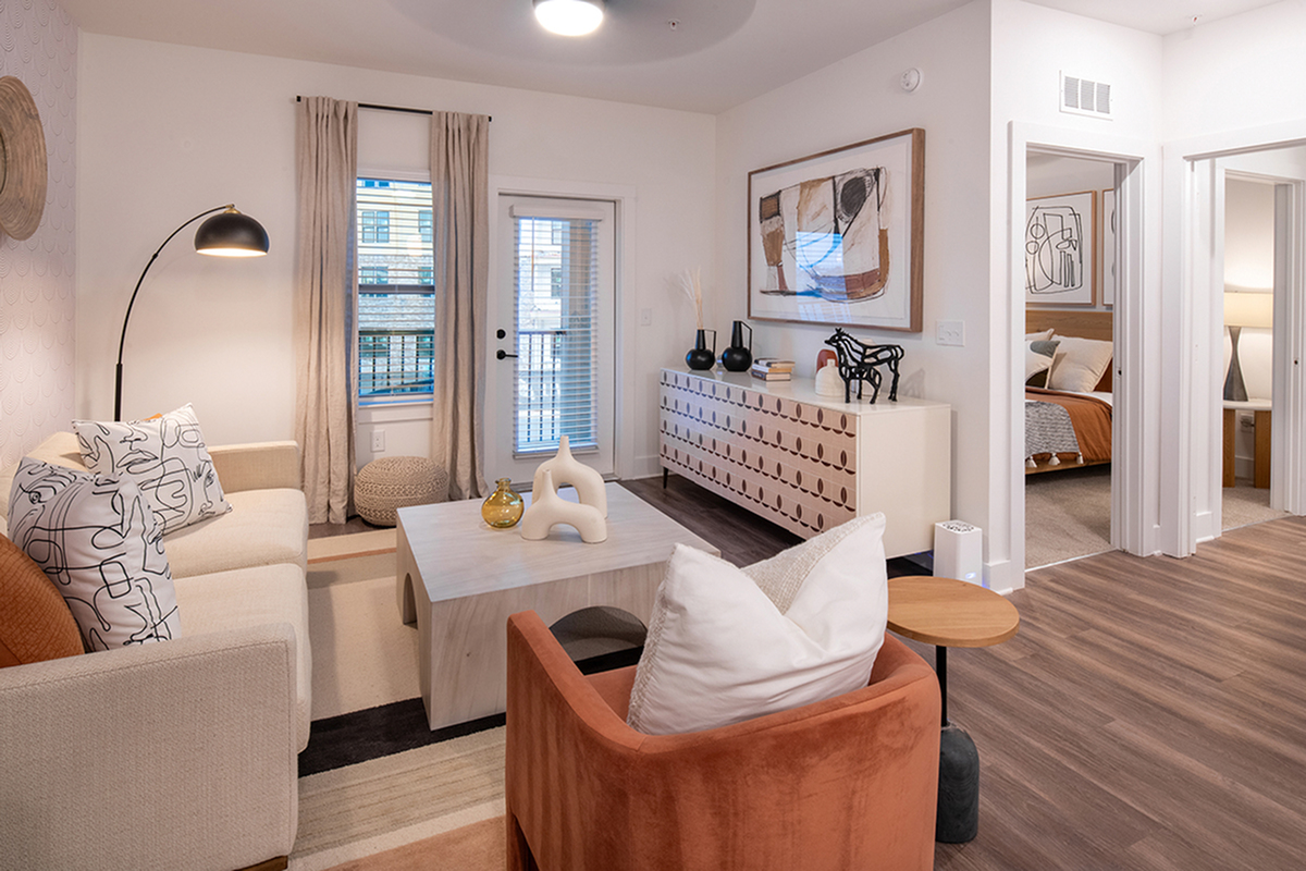 Charming living room with modern decor, cozy seating, and elegant art, leading to an inviting bedroom.
