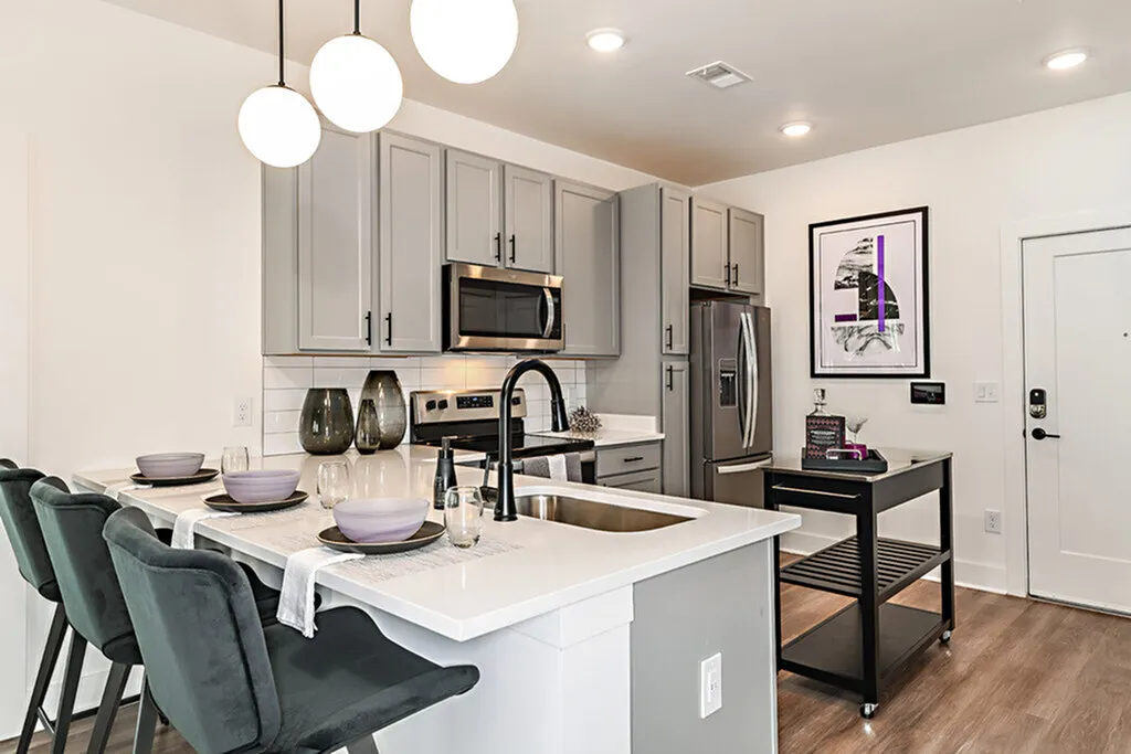 Modern kitchen with elegant countertops, stylish gray cabinetry, and a chic breakfast bar with plush seating.