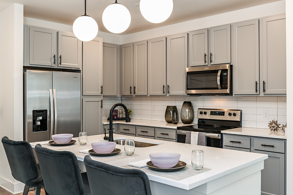 Modern kitchen with sleek gray cabinets, stainless steel appliances, and elegant pendant lighting above a spacious island.