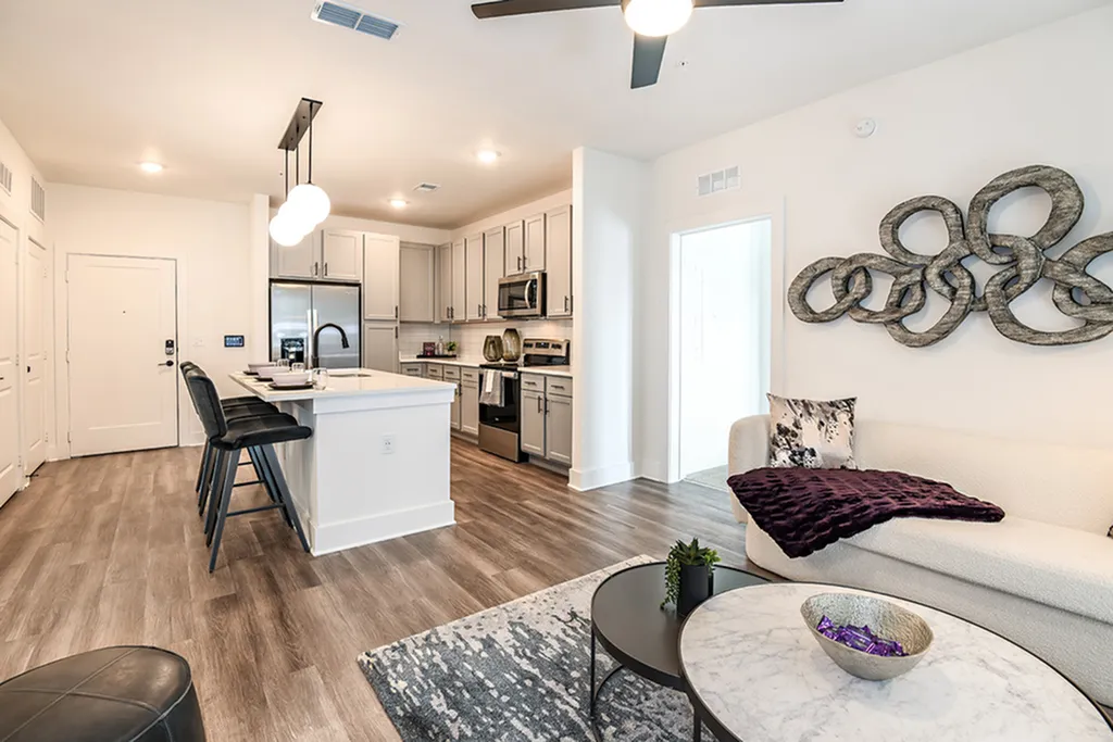 Modern open-plan kitchen and living area with sleek appliances, stylish island seating, and artistic wall decor.