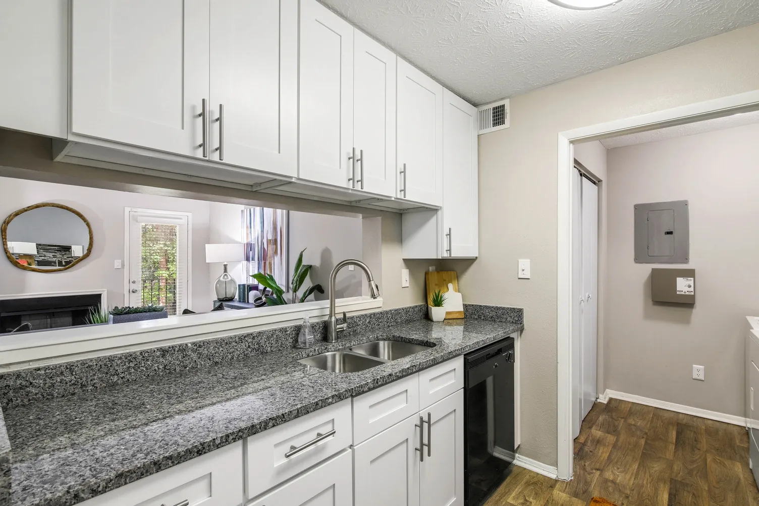 Kitchen with white cabinets, marble style countertops and hardwood style flooring.