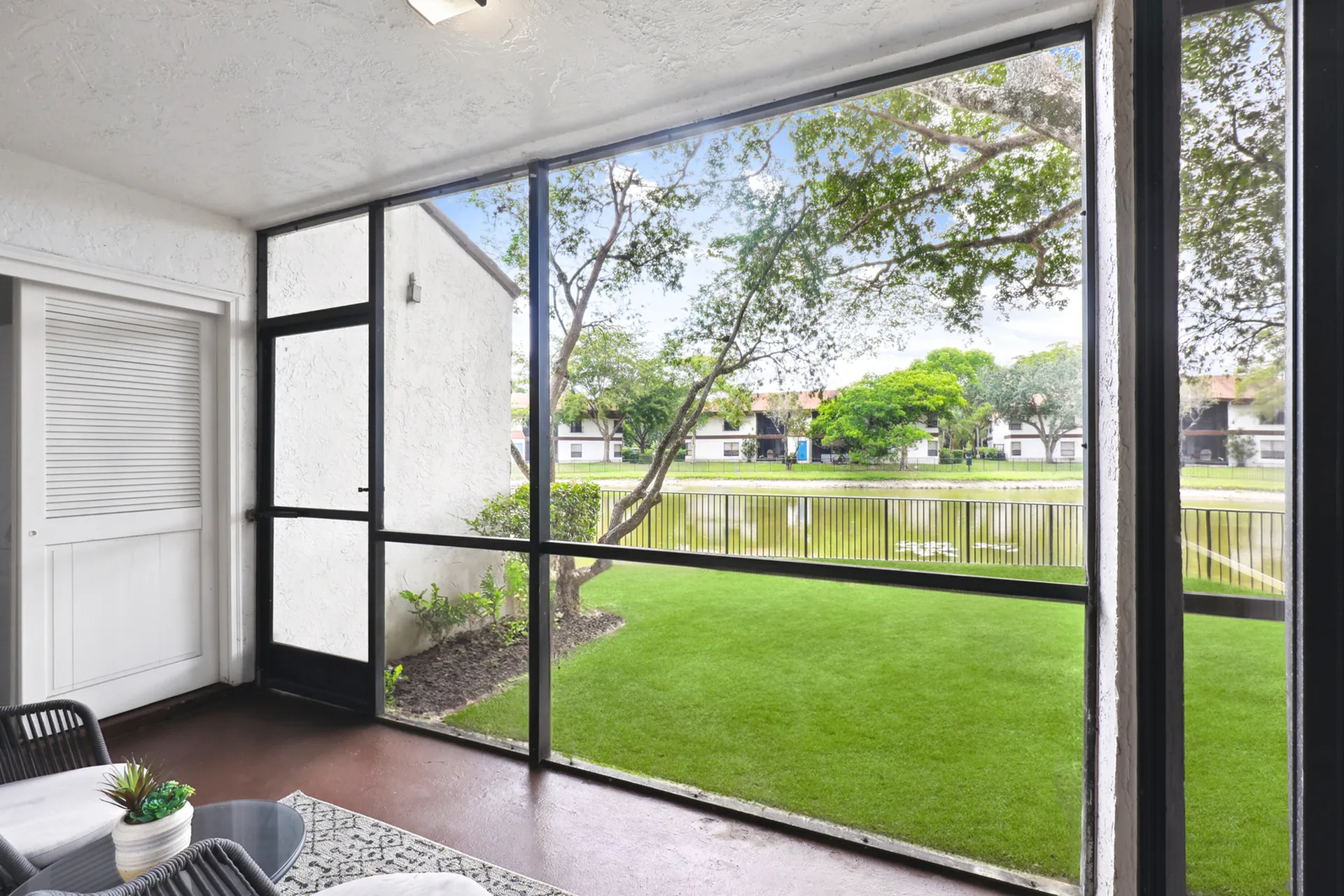 Screened in balcony with storage closet overlooking a grassy area and a lake