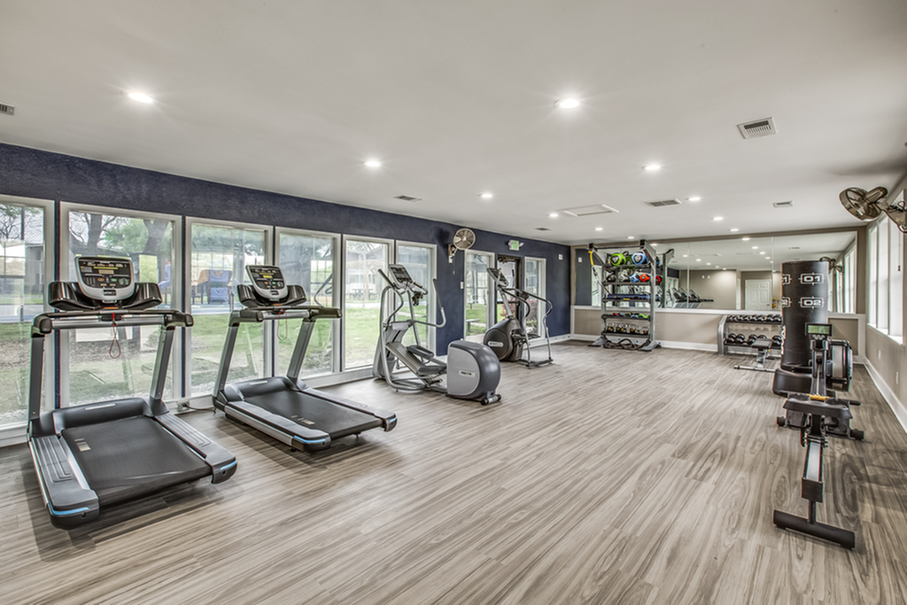 Spacious fitness center with modern gym equipment and large windows.