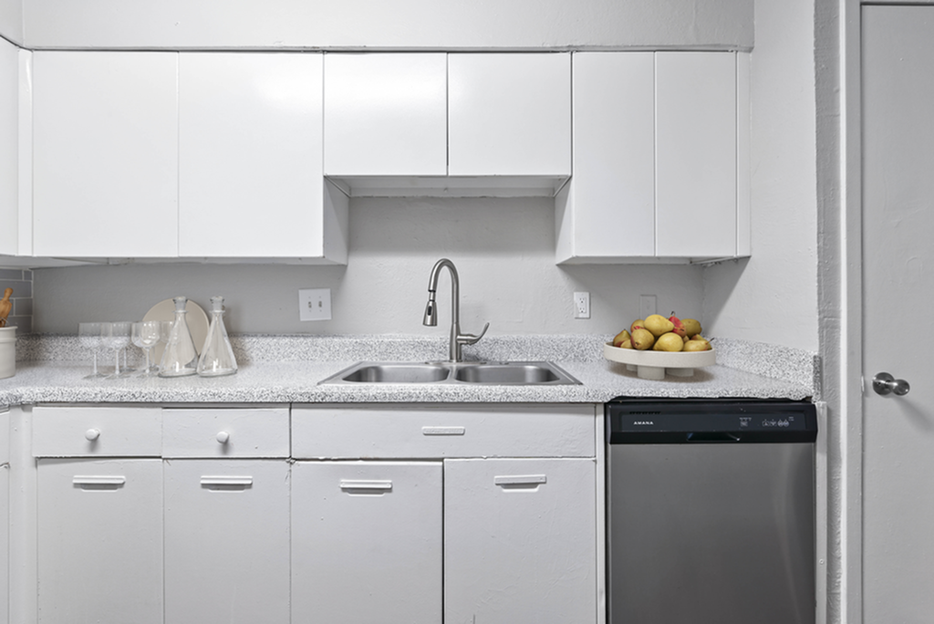 Contemporary kitchen with white cabinetry, stainless steel dishwasher, and elegant countertops.