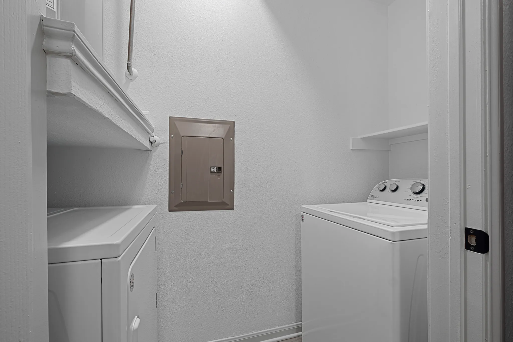 Modern laundry area featuring top-load washing machine and ample shelving, perfect for convenient in-home laundry.