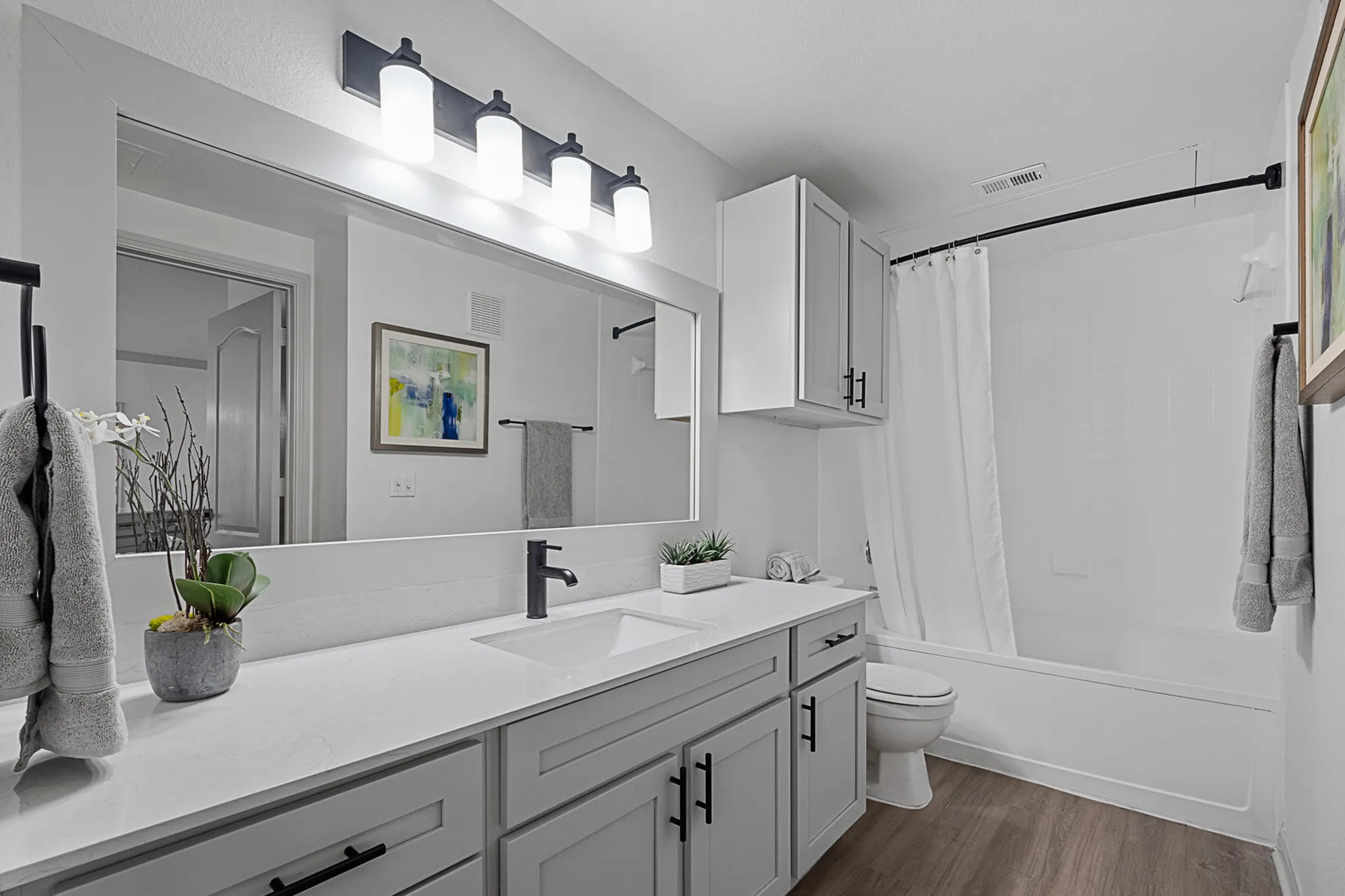 Modern bathroom with sleek white cabinetry, elegant fixtures, and a spacious mirror, exuding a fresh and inviting atmosphere.