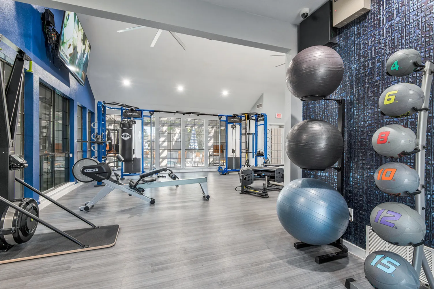 Modern fitness center with state-of-the-art equipment, including exercise balls, weight machines, and a sleek workout area with large windows.