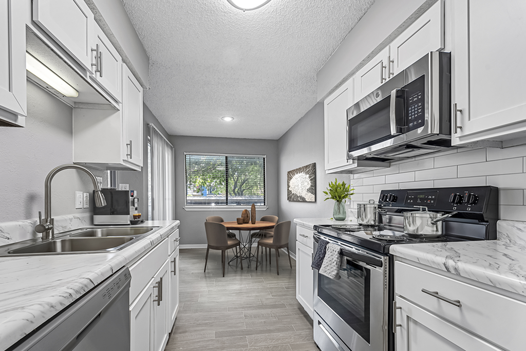 Modern kitchen with sleek stainless steel appliances, elegant marble countertops, and a cozy dining area with a scenic view.