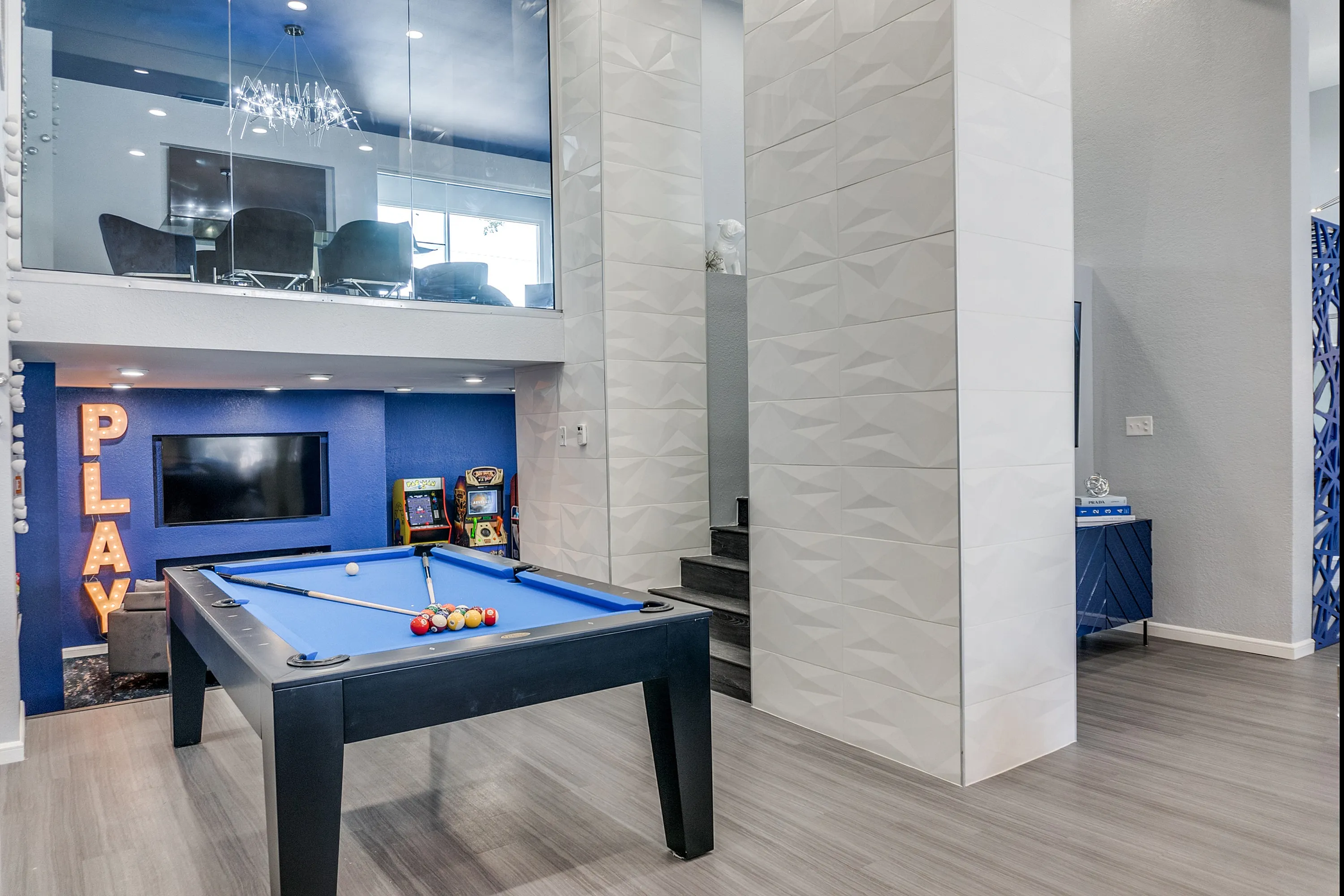Chic entertainment space with pool table and arcade games, featuring stylish lighting and modern decor.