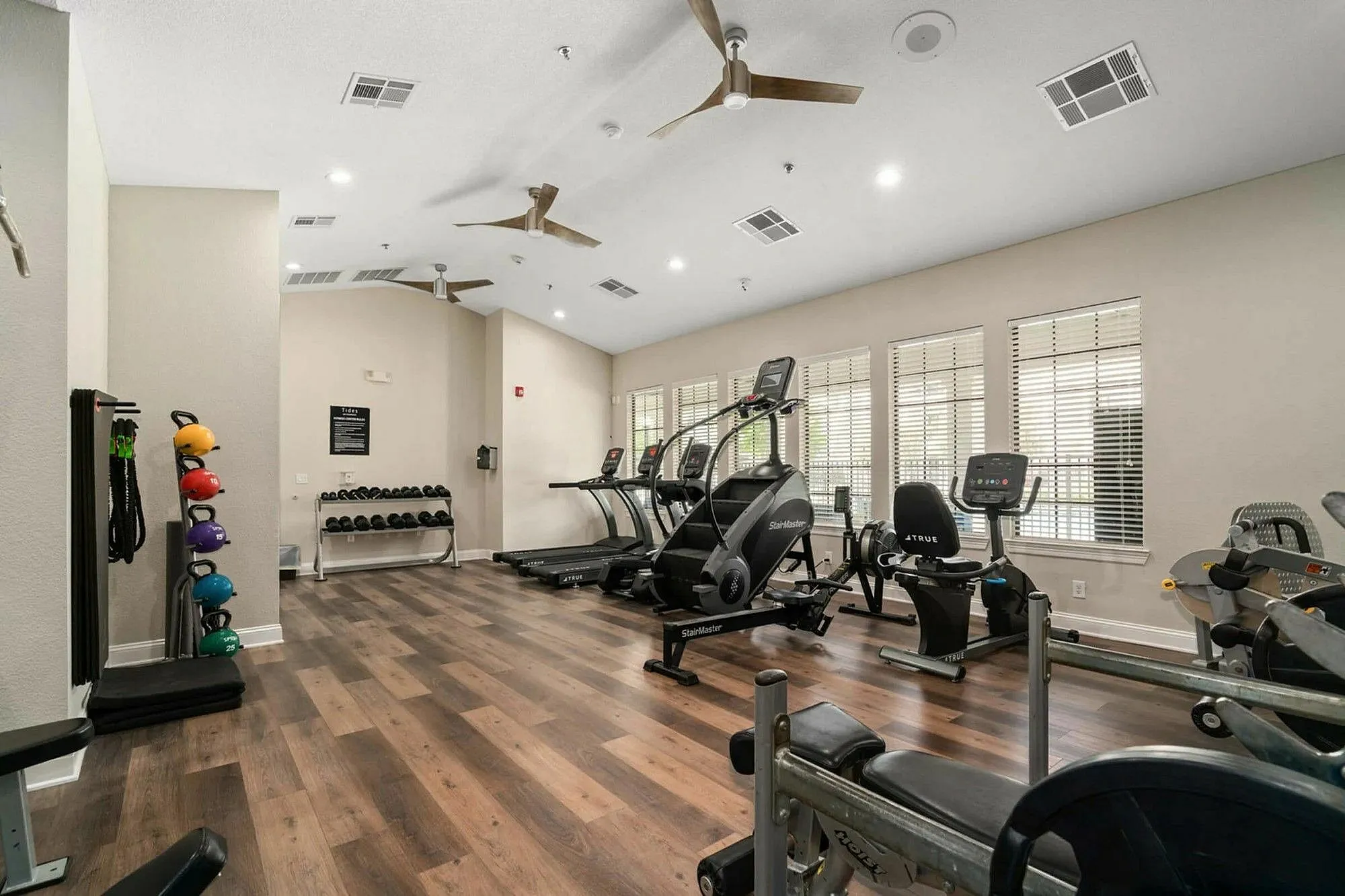 Modern fitness center with state-of-the-art treadmills, exercise bikes, and free weights on sleek, wooden flooring.