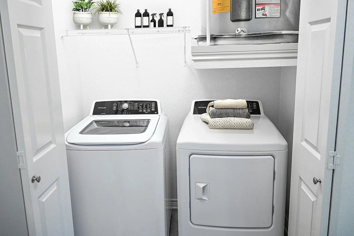 Bright laundry room featuring modern washer and dryer, elegant decor, and ample storage space for a functional and stylish home.