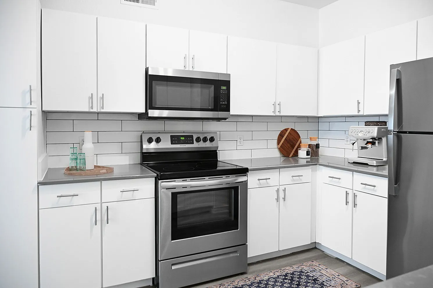 Modern kitchen with sleek white cabinets, stainless steel appliances, and stylish subway tile backsplash.