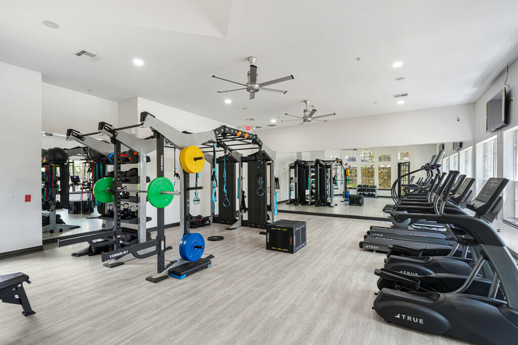 Modern fitness center with state-of-the-art equipment, ellipticals, treadmills, and ceiling fans