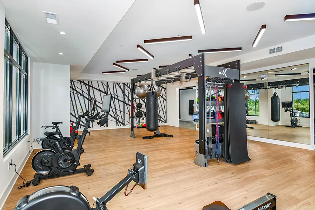 Modern fitness center with state-of-the-art gym equipment, wooden flooring, and stylish decor featuring ample natural light.