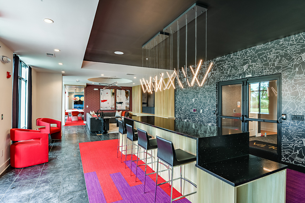Modern apartment lounge with sleek black countertops, stylish pendant lighting, and vibrant red seating for a trendy living experience.