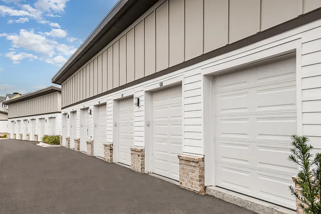 Charming row of modern garages with white paneling and brick accents under a bright blue sky, perfect for stylish urban living.