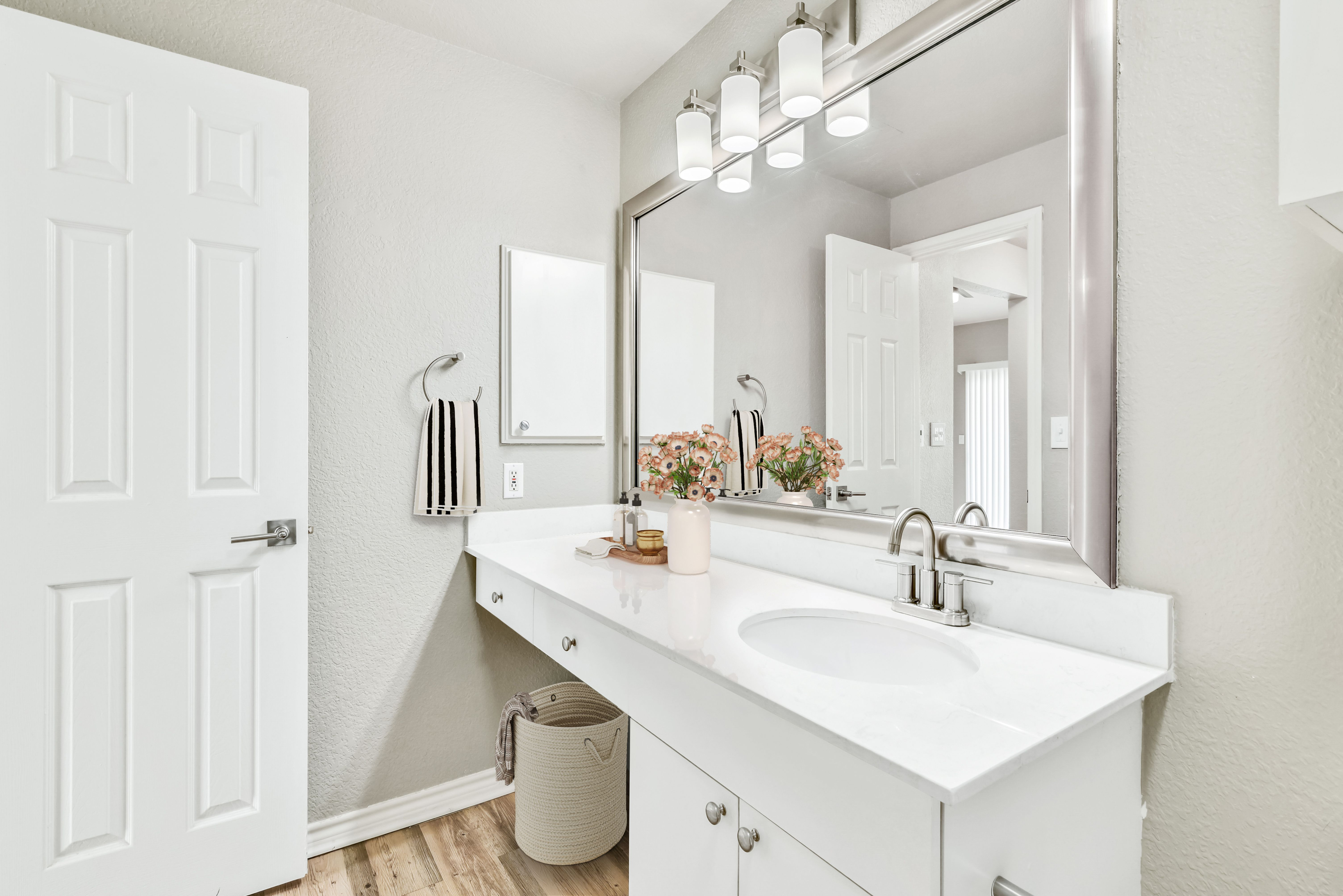 Bright and modern bathroom with sleek white cabinetry, elegant fixtures, and a large mirror reflecting soft ambient lighting.