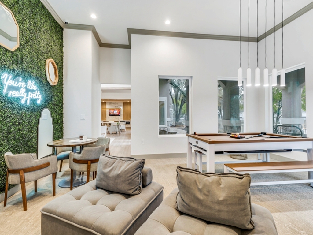 Elegant living area featuring a stylish seating arrangement, a modern pool table, and vibrant greenery wall with inspiring neon signage.